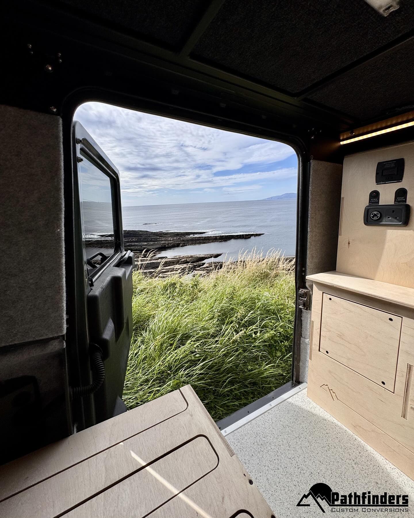 back door open of jeep with a view of the grass and the sea